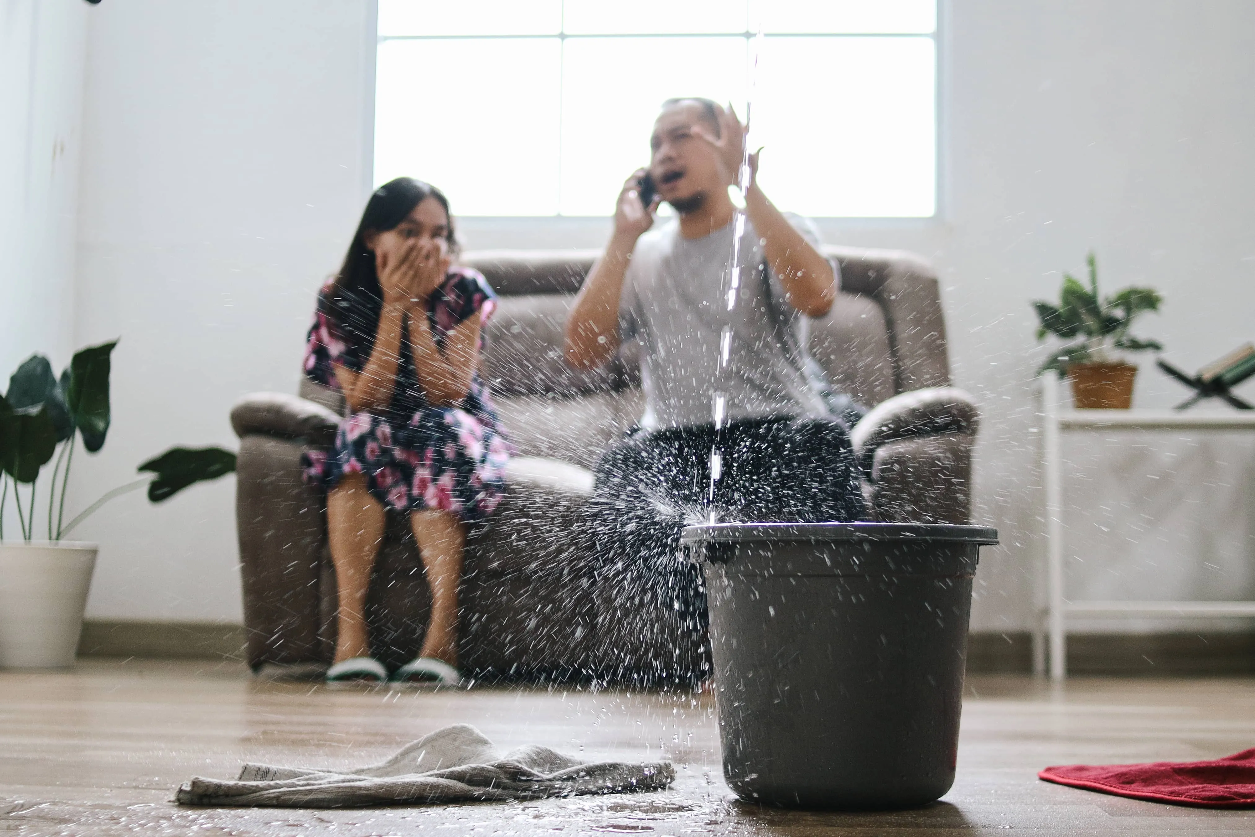 Family calling a plumber while water leaks from the ceiling